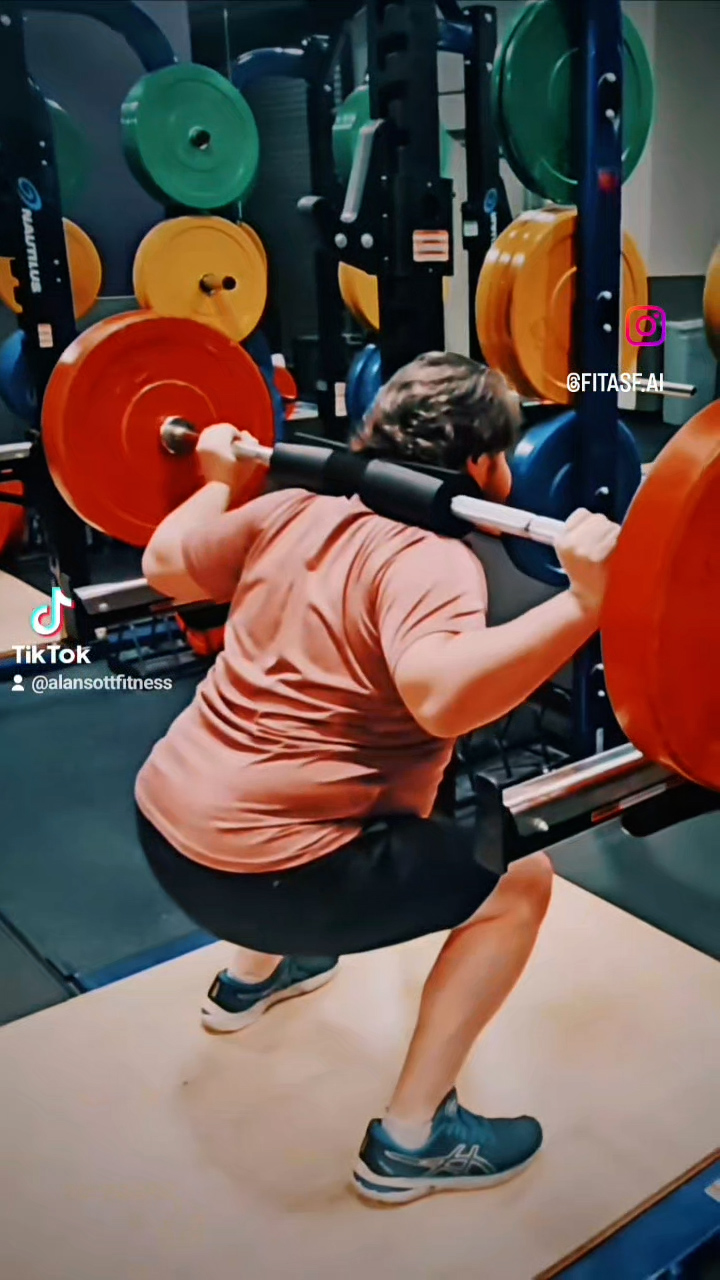 Man in his 40s doing squats with his personal trainer watching.